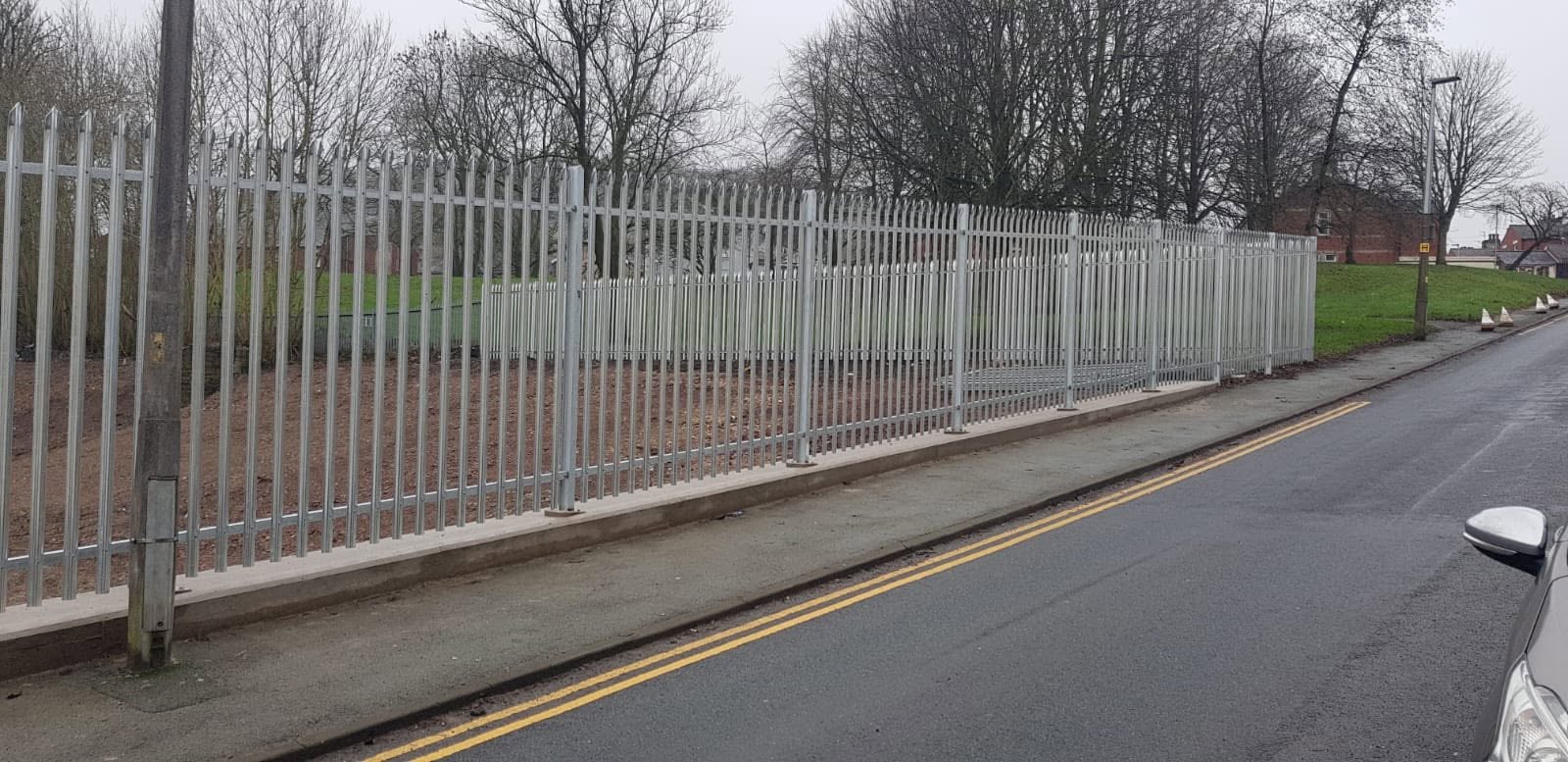 Galvanised steel palisade perimeter fencing installed alongside a roadside in the North West of England