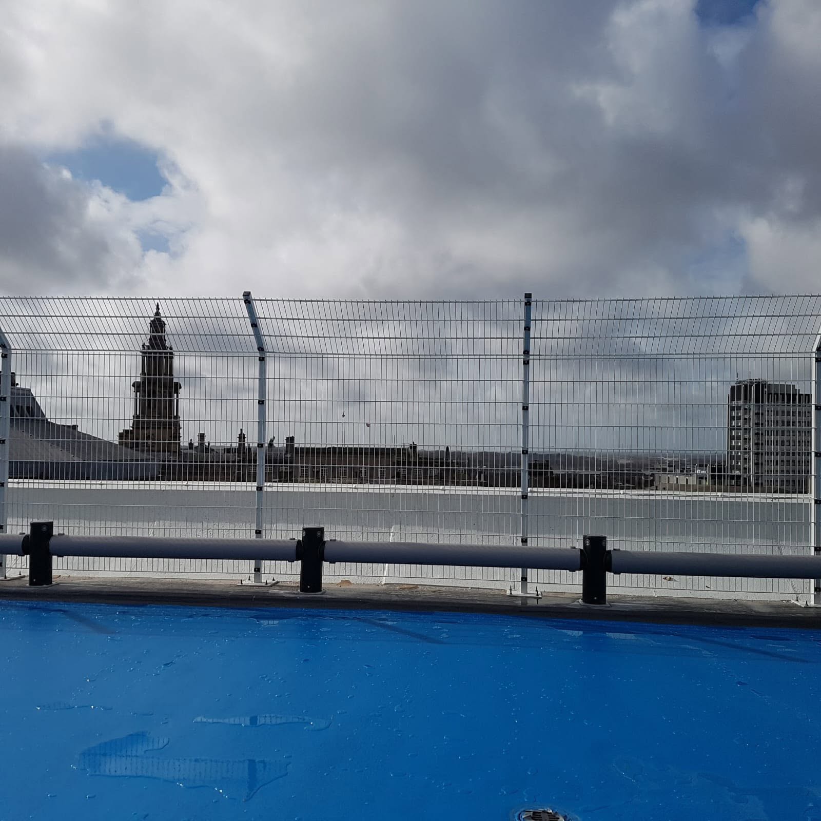 Galvanised welded mesh rooftop edge protection with curved anti-climb top and vehicle rebound rail