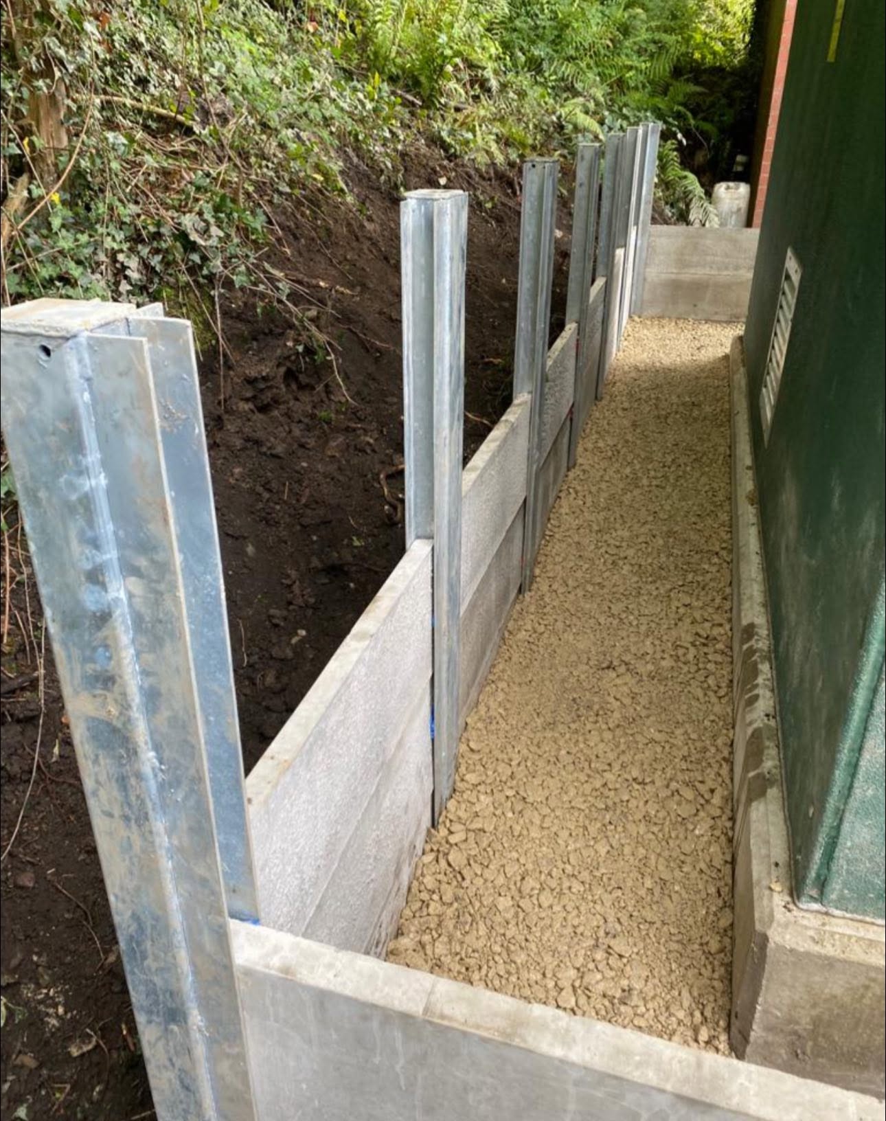 Concrete gravel boards and galvanised steel posts forming a retaining line ready for fence panels
