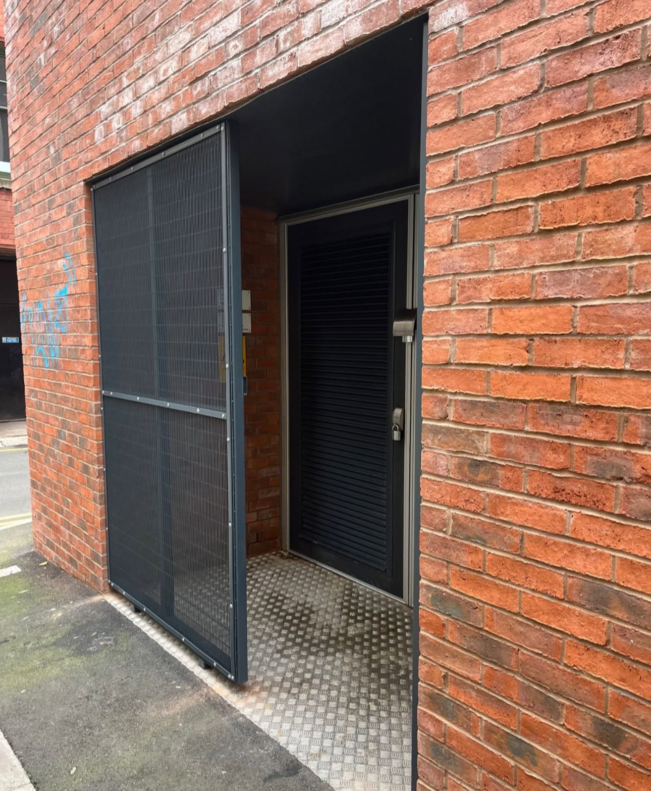 Dark grey powder-coated mesh security cage protecting a plant room doorway