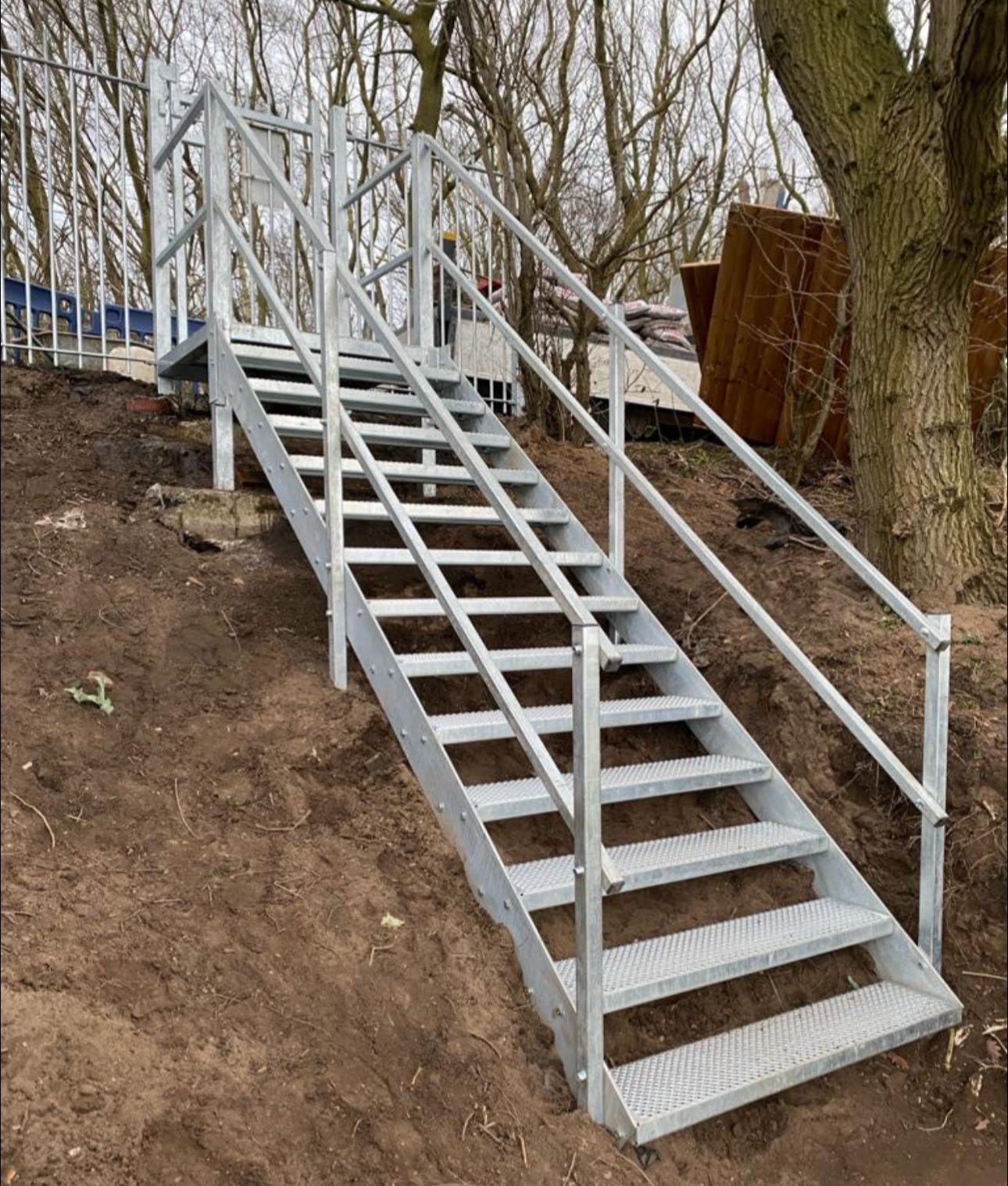 Galvanised steel access staircase with handrails installed on a landscaped bank